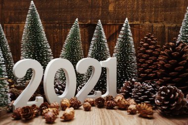 Yeni yılınız kutlu olsun. Ahşap zemin üzerinde Noel ağacı ve çam kozalağı süslemesi olan şenlikli bir geçmiş.