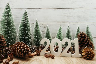Yeni yılınız kutlu olsun. Ahşap zemin üzerinde Noel ağacı ve çam kozalağı süslemesi olan şenlikli bir geçmiş.