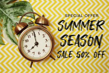 Yaz indirimi% 50 indirimli alarm saati ve sarı arka planda canavar yaprağı.