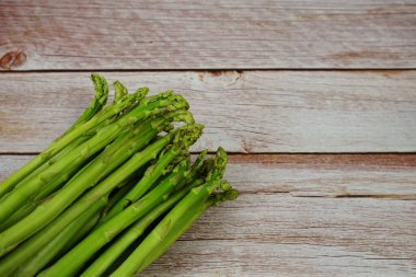 Ahşap arka planda bir sürü taze kuşkonmaz var.