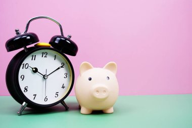 Pembe ve yeşil arka planda çalar saati olan Piggy Saving