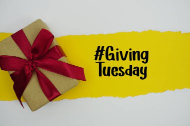 Giving Tuesday text with gift box present on yellow background