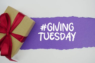 Giving Tuesday text with gift box present on purple background