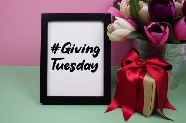 Giving Tuesday text with gift box present on pink and green background