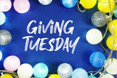 Giving Tuesday text with LED Light Cotton ball Decoration on blue background