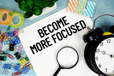 Ofis malzemeleri, bir büyüteç ve mavi ahşap bir yüzey üzerindeki bir saat ile çevrili bir kağıda daha fazla odaklanmış metin haline gel.