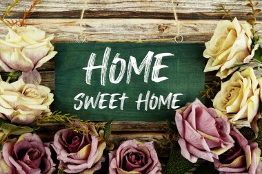 Home Sweet Home text written on wooden plank with flower decoration on wooden background