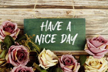 Have a Nice Day text written on wooden plank with flower decoration on wooden background