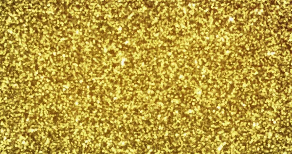 Gold glitter sparkling light shine background with golden particles texture. Shimmering sparkles and golden glowing shimmer, luxury backdrop