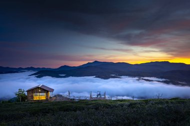 Small lovely wooden house on the edge of the valley with full of the clouds in the early morning clipart