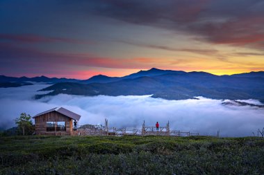 Sabahın erken saatlerinde bulutlar dolu vadinin kenarında küçük güzel ahşap ev