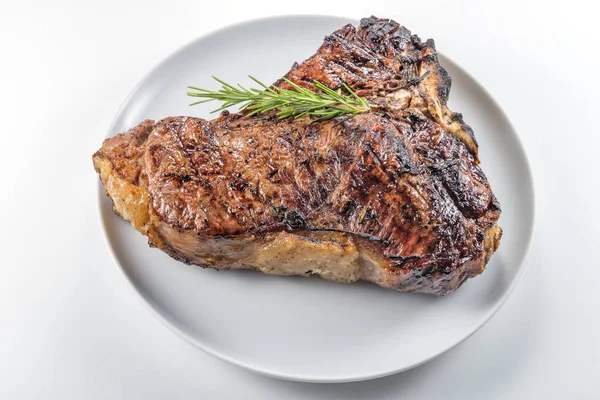 Bütün beyaz yuvarlak tabak ızgara T-bone biftek ve beyaz arka plan üzerinde izole biberiye