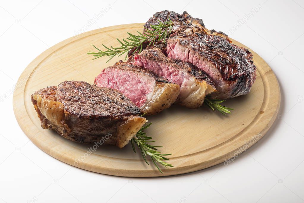 Fiorentina T-bone steak cut on round wooden chopping board isolated on white background