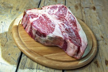 Ahşap masa üzerinde ham porterhouse biftek ile Yuvarlak Ahşap Doğrama tahtası