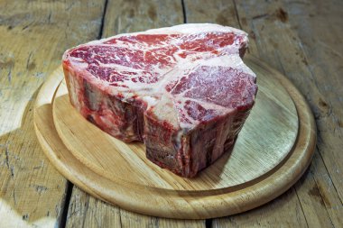 Ahşap masa üzerinde ham porterhouse biftek ile Yuvarlak Ahşap Doğrama tahtası