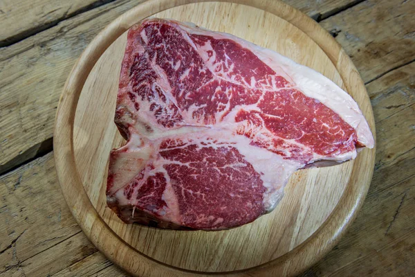 木製のテーブルで生ポーターハウス牛肉のラウンド木製のまな板 — ストック写真