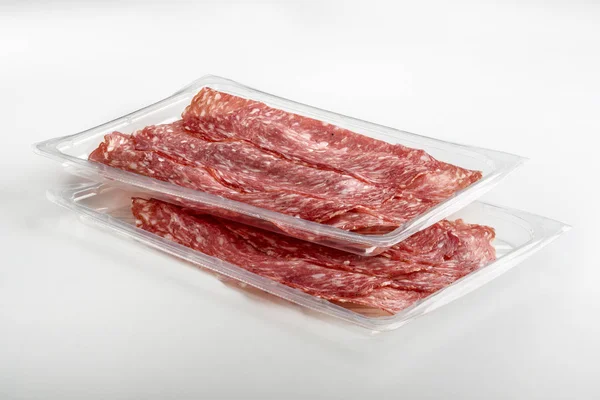 Two overlapping transparent trays of presliced Salami
