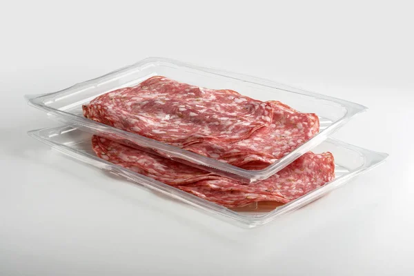 Two overlapping transparent trays of presliced Salami