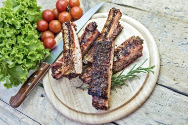 Izgara domuz pirzola domates ve salata ile yuvarlak kesme tahtası