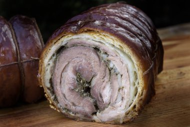 Doğrama Kurulu üzerinde yarım kesilmiş Rulo domuz eti Porchetta kavrulmuş