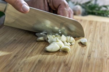 Elinde bıçakla kesme tahtası üzerinde sarımsak kıyma aşçı