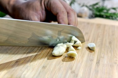 Elinde bıçakla kesme tahtası üzerinde sarımsak kıyma aşçı