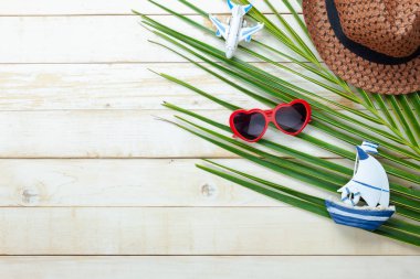 Tablo üstten görünüm yaz ve seyahat plaj veya deniz tatil sezonu arka plan kavramı hava görüntüsü. Düz temel nesne aksesuarları seyahat adam için tahta beyaz tahta üzerinde Hindistan cevizi yaprağı ile yatıyordu.