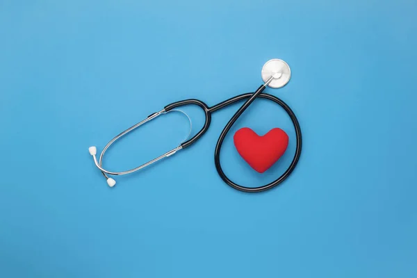 Tablo üstten görünüm aksesuarları sağlık ve tıbbi arka plan kavramı hava görüntüsü. Kırmızı kalp ve stetoskop mavi kağıt üzerinde. Doktor hastanede tedavi ve bakım hasta kullanma için düz yatıyordu temel öğeleri.