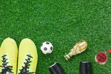 Tablo üstten görünüm hava resmi futbol ya da futbol sezonu arka planı. Düz yatıyordu aksesuarları kupa ve ayakkabı ve yapay yeşil çim duvar kağıdı üzerinde madalya ile top. Tasarım metin ve içerik için boş alan.