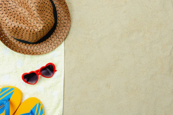 Tablo üstten görünüm havadan görüntü plaj yaz tatil arka planda seyahat etmek moda. Düz gerekli aksesuarları yatıyordu kırmızı güneş gözlüğü ve şapka ile terlik sarı peçeteye yatıyordu. Nesneler üzerinde beyaz kum.