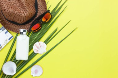 Tablo üstten görünüm yaz ve seyahat plaj tatil sezonu arka plan kavramı içinde hava görüntüsü. Düz yatıyordu gerekli aksesuarları seyahat için. Beyaz losyon ve sarı kağıt zemin üzerinde giyim nesneleri.