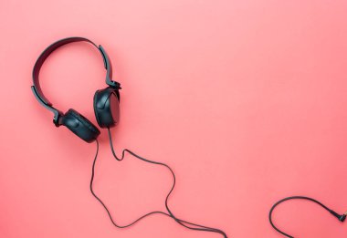 Tablo üstten görünüm radyo müzik arka plan kavramı dinleme aksesuarları hava görüntüsü. Rustik pembe kağıt modern duvar kağıdı düz yatıyordu siyah kulaklık. Yaratıcı tasarım metin ve içerik için boş alan.