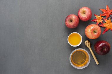 Masa üstü Rosh Hashana arka plan kavramı süslemeleri Yahudi tatil hava görüntüsünü görüntüleyin. Düz çeşitli elma ve bal arı nesne iz Kupası ve tahta kaşık modern rustik gri ahşap duvar üzerinde yatıyordu.