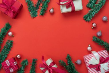 Merry Christmas dekorasyon ve mutlu yeni yıl süsleri kavramı en iyi görünümünü masa. Düz yatıyordu temel fark nesneleri hediye kutusu ve köknar ağacı ev stüdyosu ofis masası, kırmızı kağıt modern arka plan üzerinde.