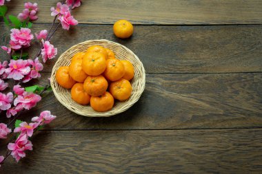 Tablo üstten görünüm ay yeni yıl ve Çin yeni yıl tatili kavramı arka plan. Düz yatıyordu turuncu ahşap sepet ve yaratıcı tasarım modern rustik kahverengi backdrop.free alan üzerinde pembe kiraz çiçeği.