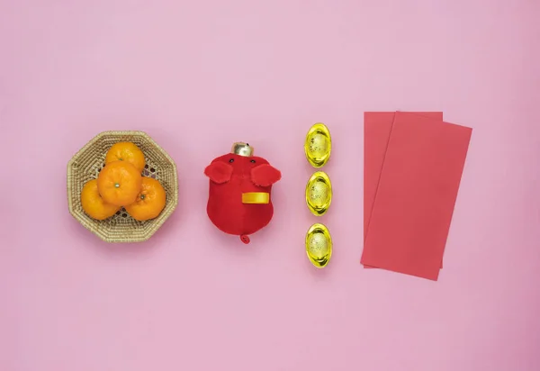 Chinese language mean rich or wealthy and happy.Table top view Lunar New Year & Chinese New Year concept background.Flat lay orange & pig doll with gold money and red pocket money card on pink paper.