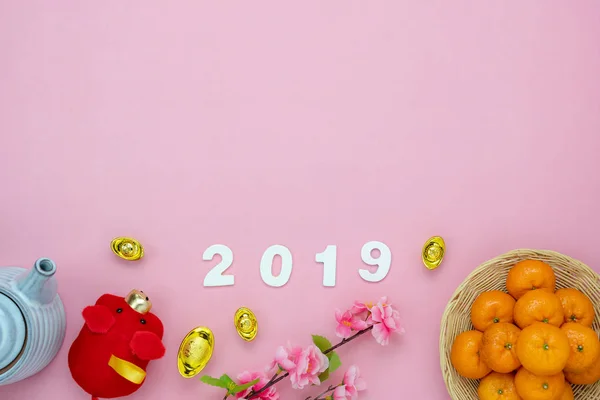 Chinese language mean rich or wealthy and happy.Table top view Lunar New Year & Chinese New Year 2019 vacation concept background.Flat lay mix variety object the orange & pig doll on pink paper.