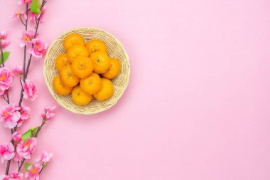 Masa üstü dekorasyon görüntüleyin veya ay yeni yıl ve Çince yeni yıl kavramı arka plan süsleme. Düz pembe paper.creative tasarımı için sahte kiraz çiçeği ile turuncu ahşap sepet içinde nesne yığmak