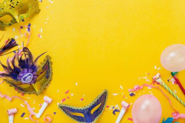 Tablo en iyi görünüm güzel renkli süslemeleri karnaval festival arka plan hava görüntüsü. Düz aksesuar nesne maske ve dekor konfeti ve pembe balon modern sarı paper.copy alanı üzerinde yatıyordu..