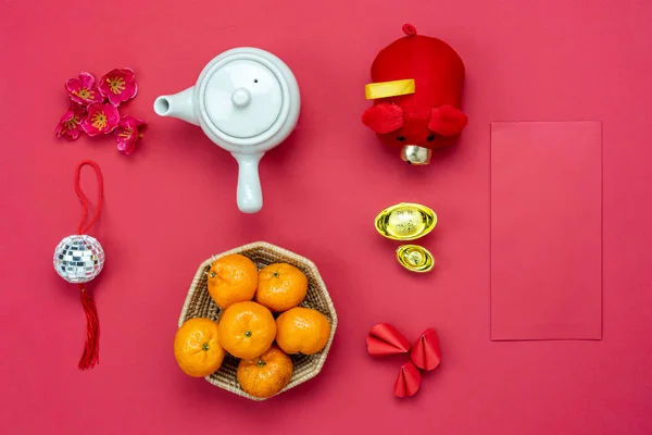 Chinese language mean rich or wealthy and happy.Table top view Lunar New Year & Chinese New Year.Flat lay orange and pig doll toy kid with cherry blossom and cookie fortune decor on modern red paper.