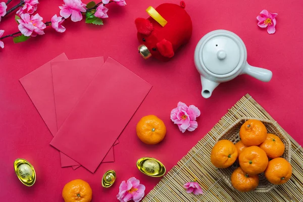 Chinese language mean rich or wealthy and happy.Table top view Lunar New Year & Chinese New Year concept background.Flat lay orange & pig doll with flower and fortune season decorations on red paper.