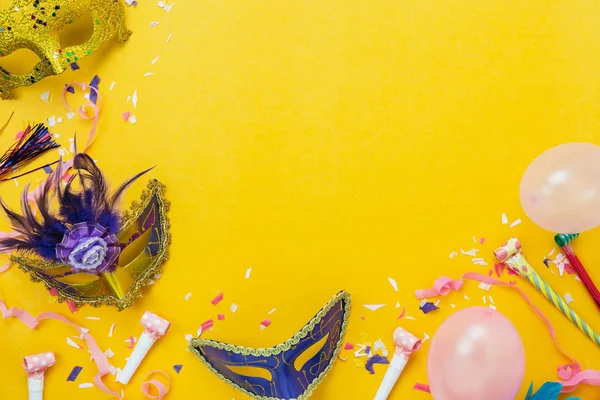 Tablo en iyi görünüm güzel renkli süslemeleri karnaval festival arka plan hava görüntüsü. Düz aksesuar nesne maske ve dekor konfeti ve pembe balon modern sarı paper.copy alanı üzerinde yatıyordu..