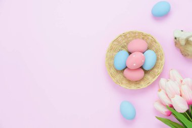 Tablo üstten görünüm süslemeleri mutlu Paskalya tatili arka plan kavramı bir kadeh. Düz düzenleme bunny ahşap sepeti ve Lale ile modern rustik pembe kağıt üzerinde yumurtlamak. Yaratıcı tasarım metin için yer kopyalayın
