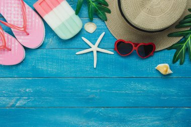 Kıyafet kadınların masa üstü görünüm aksesuar yaz tatili arka plan kavramı seyahat planlıyoruz. Modern rustik mavi ahşap üzerinde birçok temel öğeleri şapka ve güneş gözlüğü ile dondurma. Tasarım alanı.