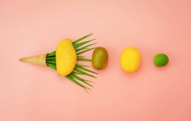 İlkbahar yaz tatili ve tatil arka plan konsepti ile masa üstü görünümü meyve tropikal. Düz lay düzenleme pembe kağıt üzerinde dondurma konisi ile çeşitli ananas kivi mango limon ve kireç dilimlenmiş.