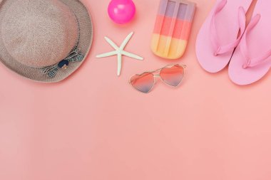 Giysi kadın masa üstü görünüm aksesuar yaz tatili arka plan kavramı. Monstera modern rustik pembe kağıt üzerinde temel öğeleri güneş gözlüğü ve terlik ile yaprakları seyahat planlıyoruz. Tasarım alanı.