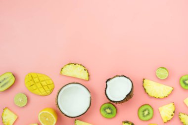 Bahar yaz tatil ve tatil arka plan kavramı ile tablo üst görünüm meyve tropikal. Düzenleme pembe kağıt üzerinde çeşitli ananas kivi Mango limon ve kireç Hindistan cevizi dilimlenmiş. düz Lay & kopya alanı.