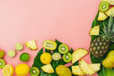 İlkbahar yaz tatili ve tatil arka plan konsepti ile masa üstü görünümü meyve tropikal. Düzenleme monstera yeşil yaprakları çeşitli ananas mango limon ve kireç dilimlenmiş. Pembe kağıt üzerinde öğeler.pastel.