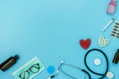 Masa üstü görünüm aksesuar sağlık ve tıbbi arka plan kavramının havadan görüntü. Kırmızı kalp ve stetoskop mavi kağıt üzerinde temel nesneleri ile. Hastanede doktor tedavi hasta için fikir Düz yatıyordu.