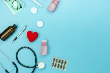 Masa üstü görünüm aksesuar sağlık ve tıbbi arka plan kavramının havadan görüntü. Kırmızı kalp ve stetoskop mavi kağıt üzerinde temel nesneleri ile. Hastanede doktor tedavi hasta için fikir Düz yatıyordu.